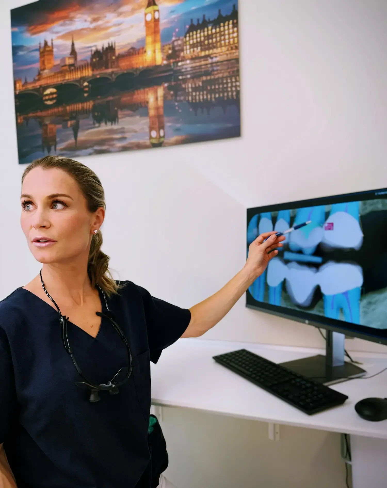 Tannlege peker på røntgenbilde på skjerm for pasient